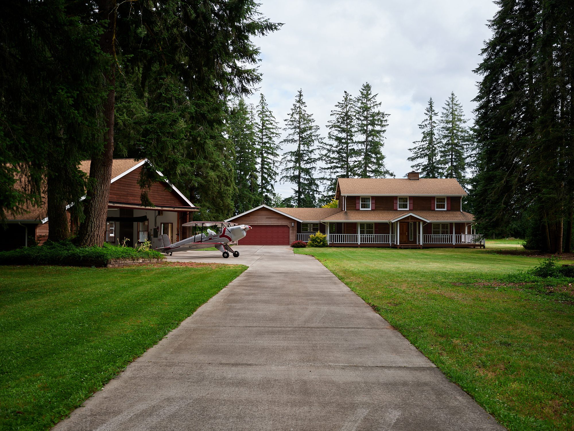 The driveway approach to the home, with the hangar and a parked biplane at Parkside Airpark