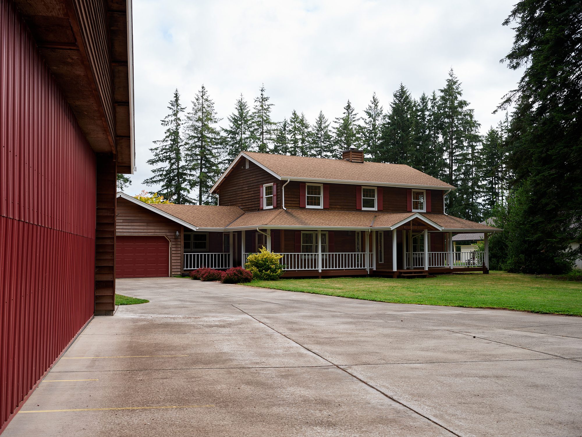 Concrete taxi apron between the red hangar and the home with its wraparound porch