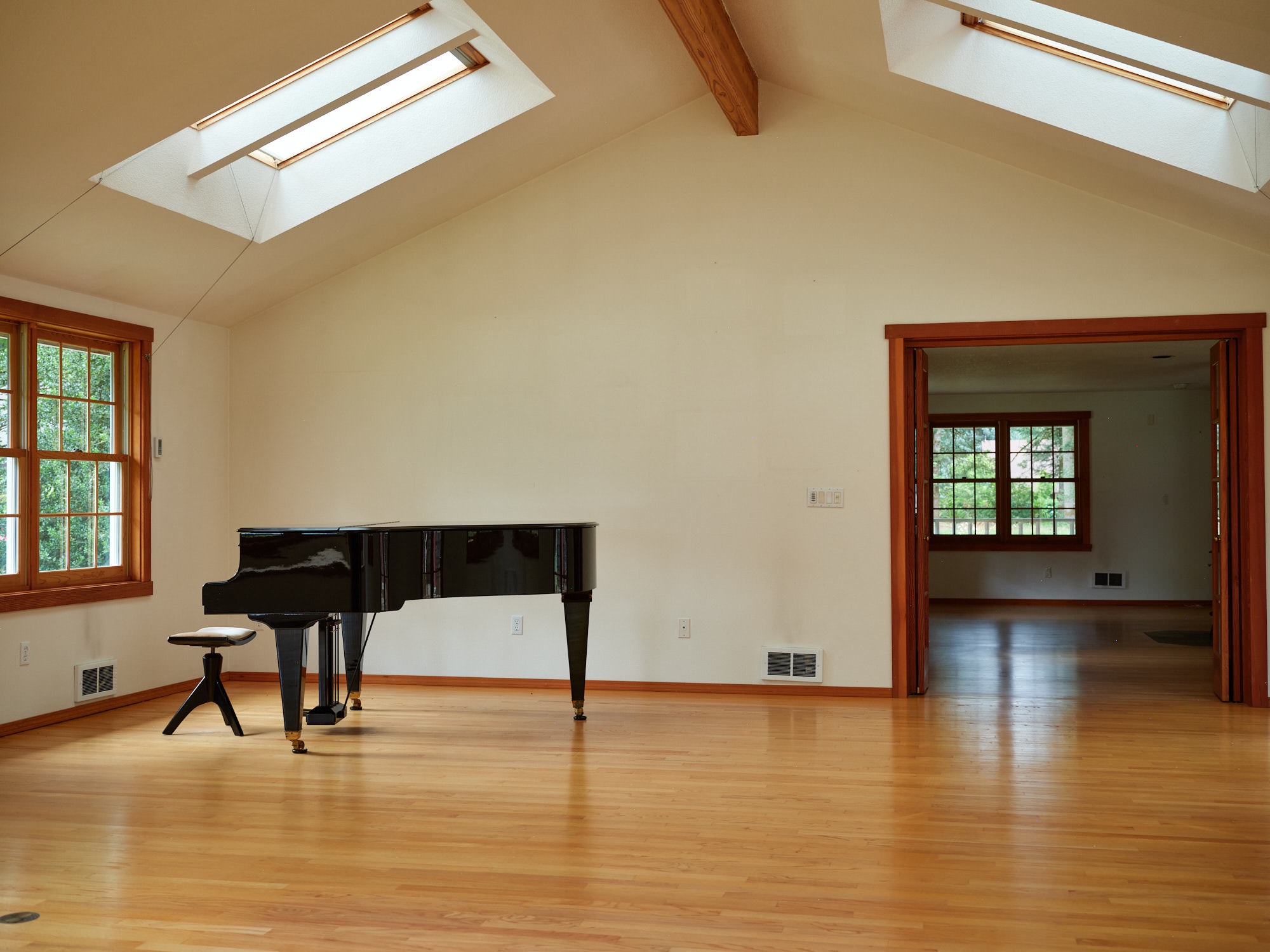 Vaulted great room with exposed beams, skylights, and hardwood floors