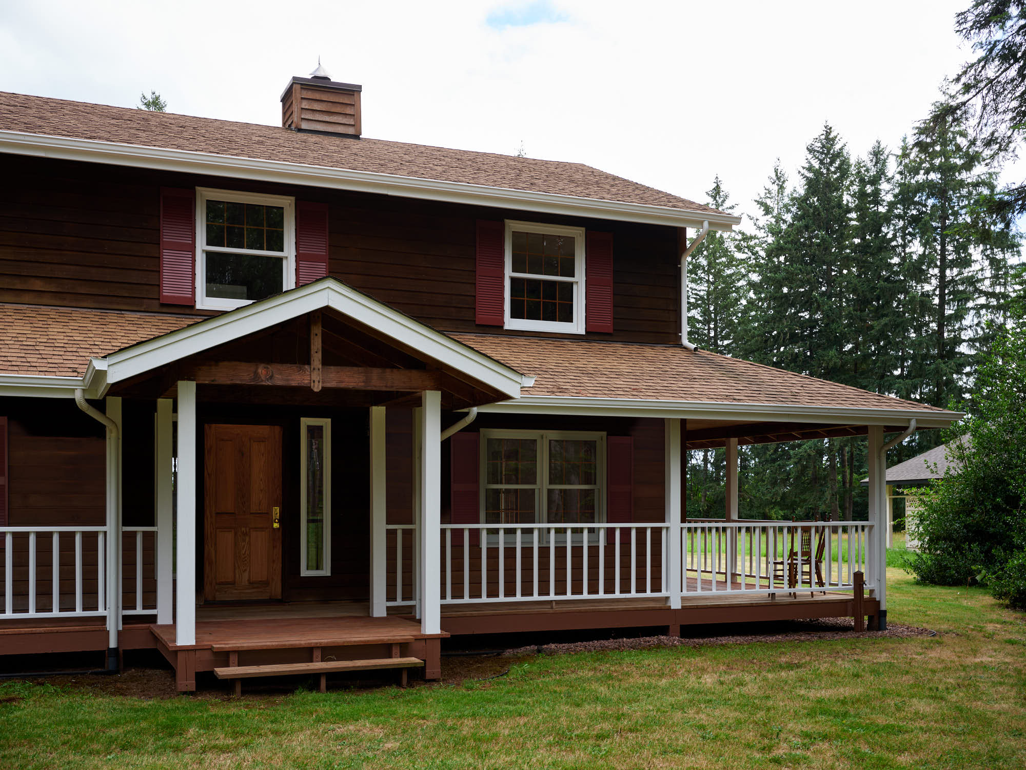 Covered wraparound porch along the front of the cedar home